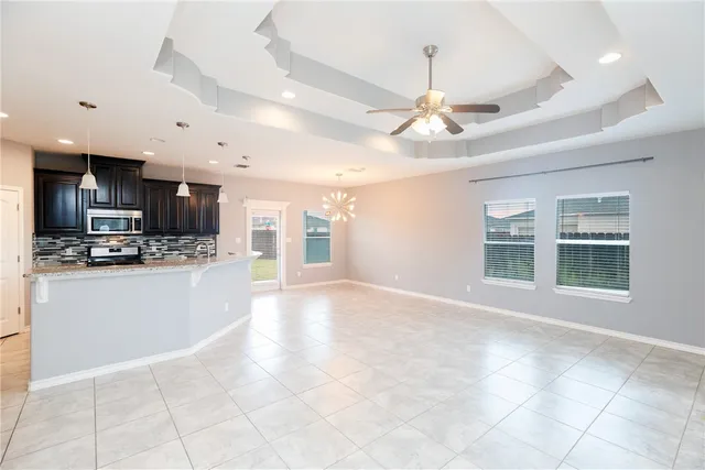 a view of an empty room with kitchen and window