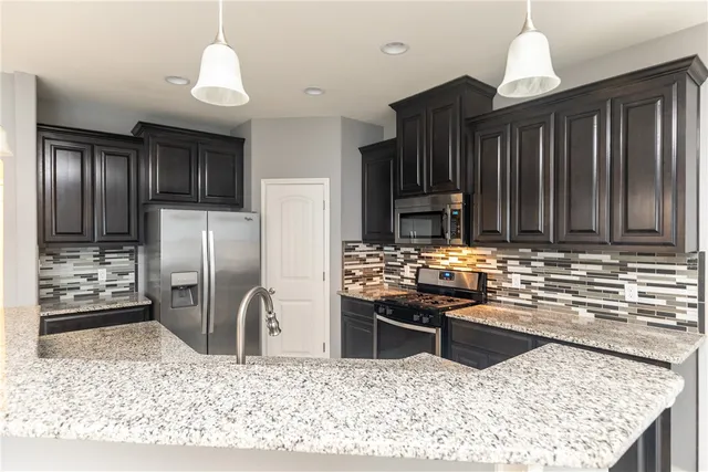 a kitchen with stainless steel appliances granite countertop a refrigerator a stove and a sink