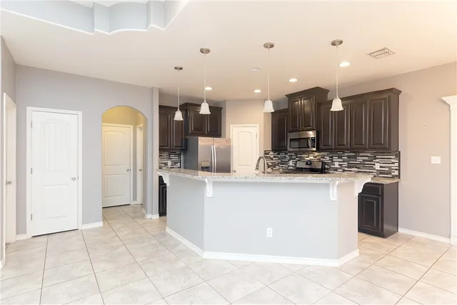a view of kitchen with stainless steel appliances kitchen island granite countertop a refrigerator and a stove top oven