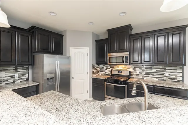 a kitchen with stainless steel appliances kitchen island granite countertop a refrigerator and a sink