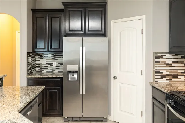 a kitchen with kitchen island granite countertop a refrigerator and a stove