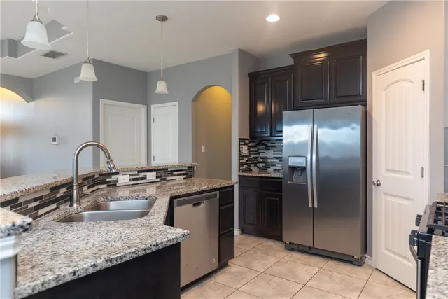 a kitchen with stainless steel appliances granite countertop a sink stove and refrigerator
