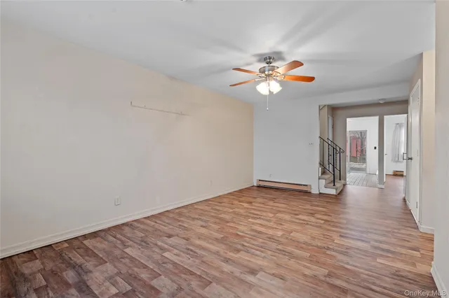 a view of an empty room with chandelier fan and wooden floor
