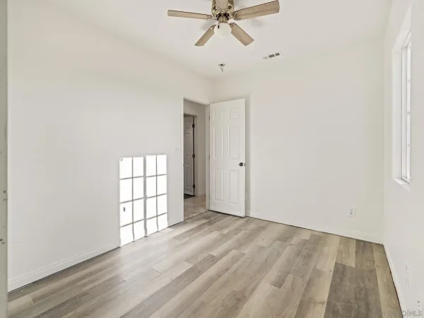 an empty room with windows and fan