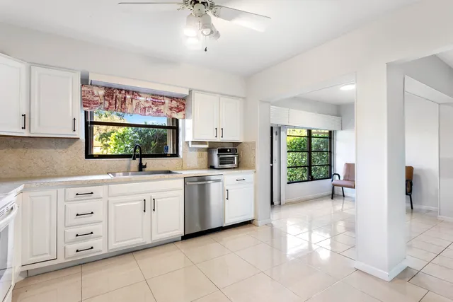 a kitchen with white cabinets and window