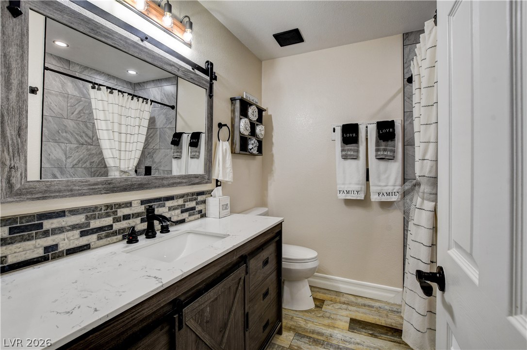 6460 Racel Street Las Vegas, NV 89131 - Photo 54 of 59 A modern vanity with stone counters and a tile backsplash highlights this updated bathroom.