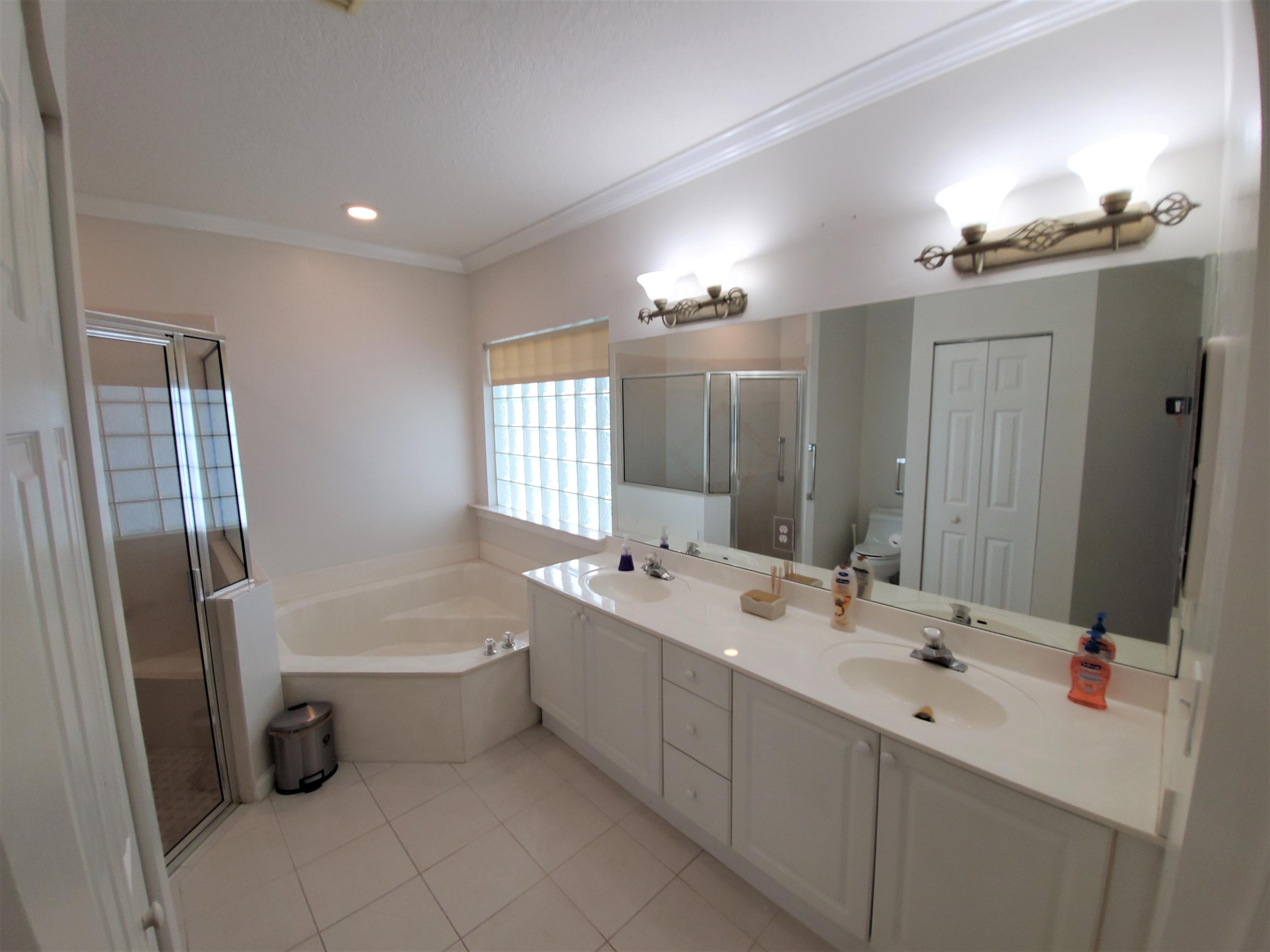 9897 Sandy Run Road Jupiter, FL 33478 - Photo 14 of 30 a bathroom with a double vanity sink a toilet a mirror and shower