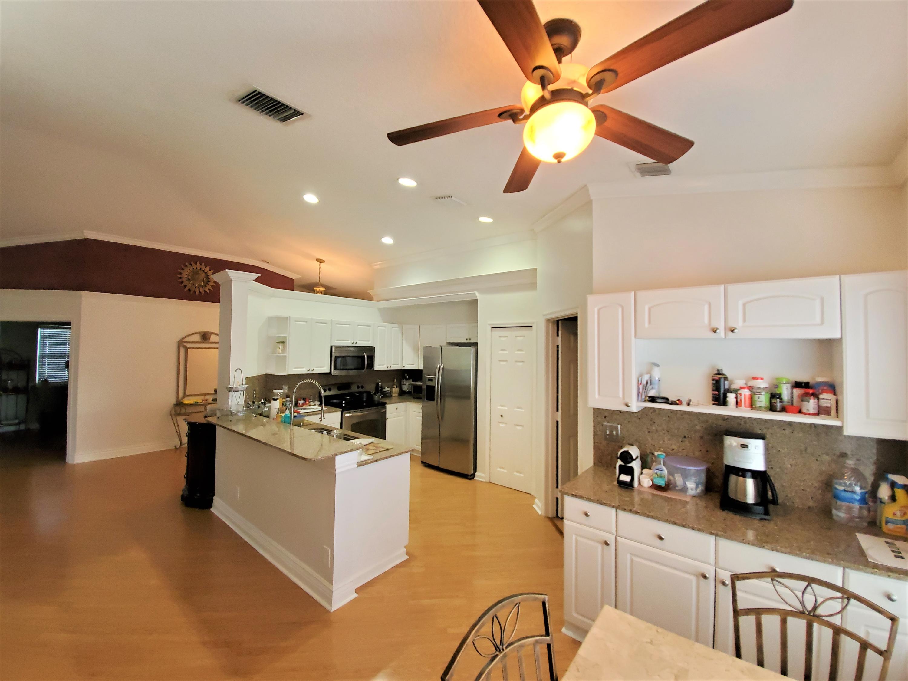 9897 Sandy Run Road Jupiter, FL 33478 - Photo 5 of 30 a kitchen with stainless steel appliances kitchen island granite countertop a sink cabinets and refrigerator