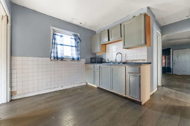 a kitchen with granite countertop a sink cabinets and wooden floor