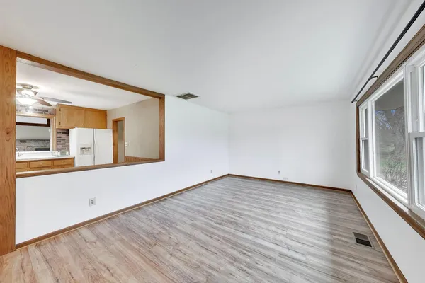 a view of an empty room with wooden floor and a window