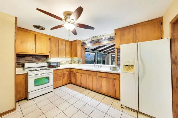 a kitchen with stainless steel appliances granite countertop a refrigerator a sink a stove a dining table and chairs with wooden floor