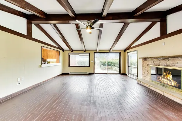 a view of empty room with wooden floor and fireplace