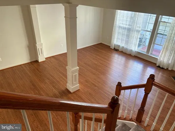 a view of an empty room with wooden floor and windows