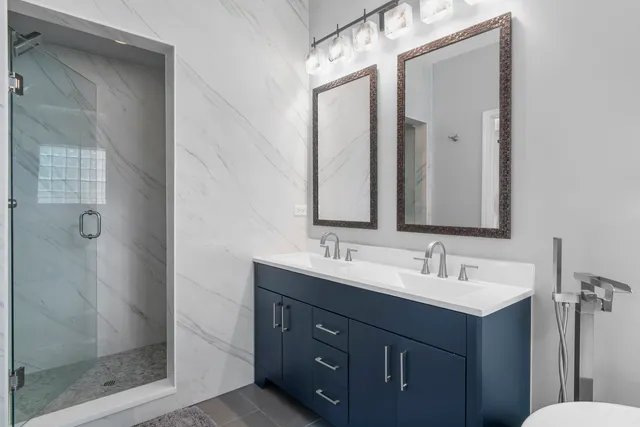 a bathroom with a double vanity sink mirror and shower