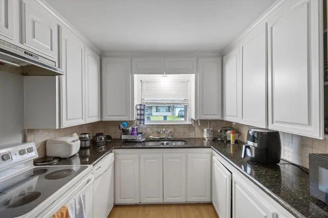 a kitchen with granite countertop a sink a stove and cabinets
