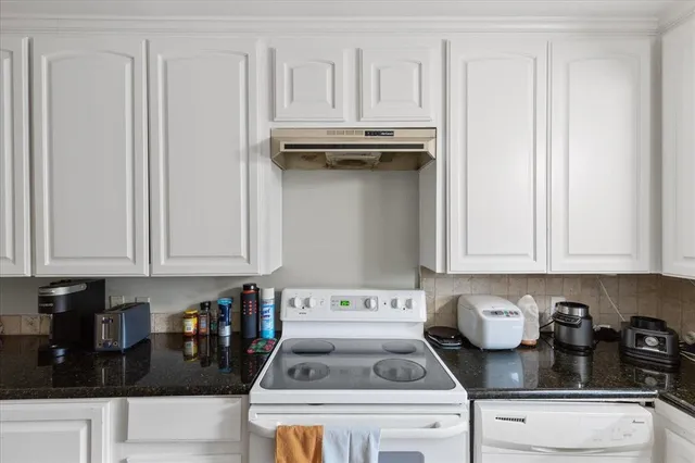 a kitchen with a stove and white cabinets