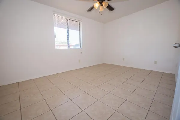 an empty room with a chandelier fan and windows