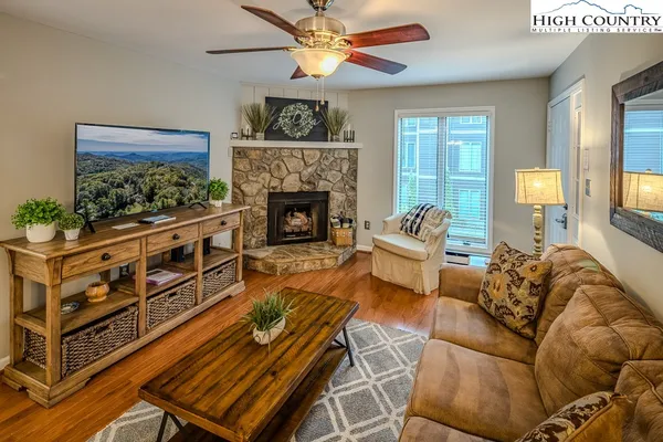 a living room with furniture a fireplace and a ceiling fan