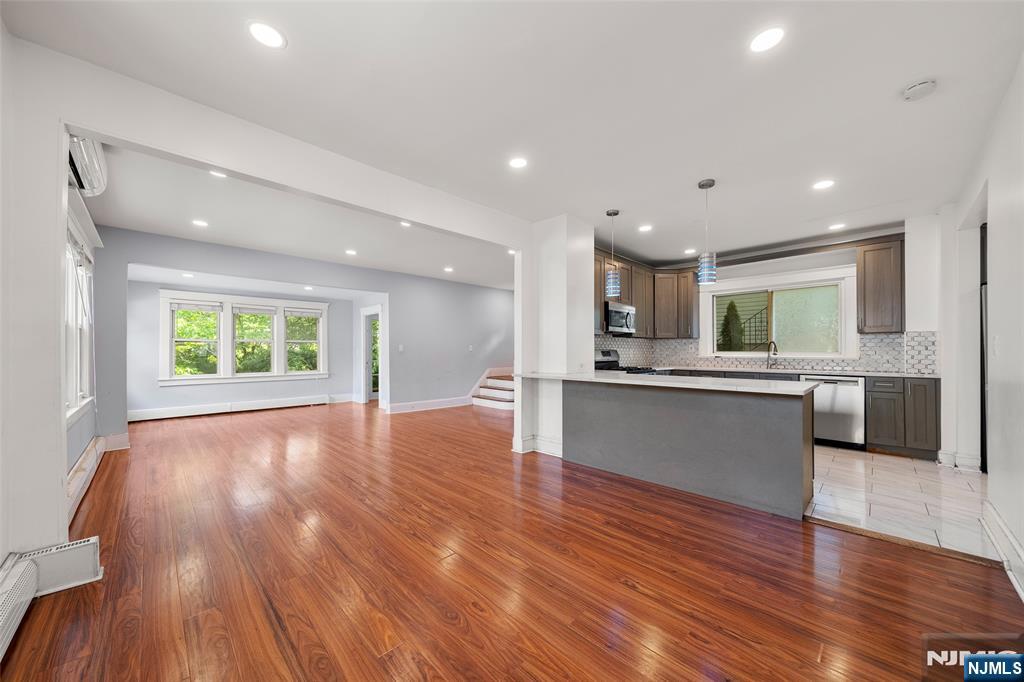 a view of kitchen with kitchen island wooden floor center island stainless steel appliances and window