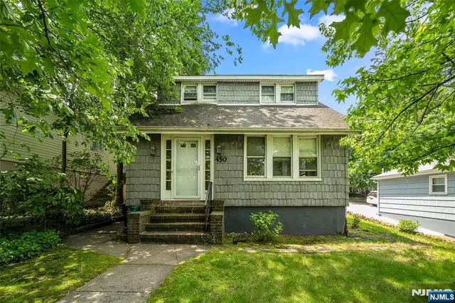a view of a house with a yard plants and large tree