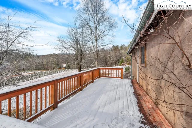a balcony with wooden floor and trees in the background