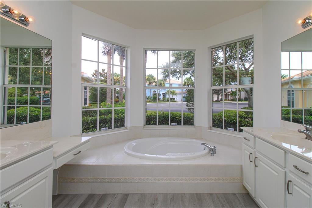 3927 Aurora Court Naples, FL 34116 - Photo 19 of 26 Full bath with two vanities, a garden tub, and plenty of natural light