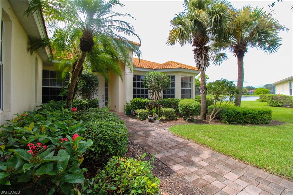 3927 Aurora Court Naples, FL 34116 - Photo 2 of 26 Entrance to property featuring stucco siding, a lawn, and a tiled roof
