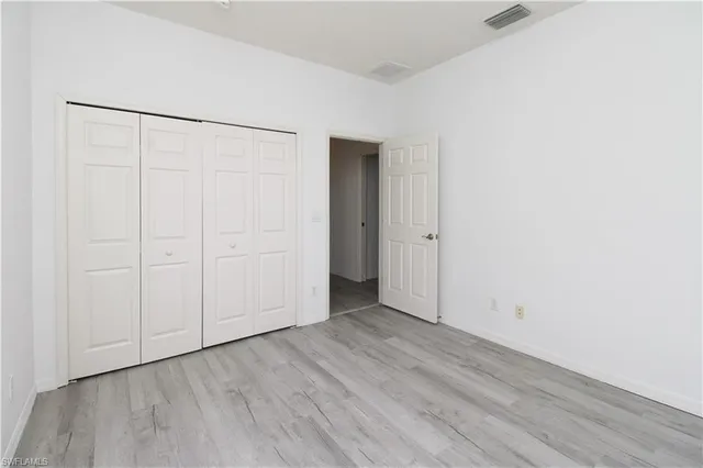 an empty room with wooden floor and closet area