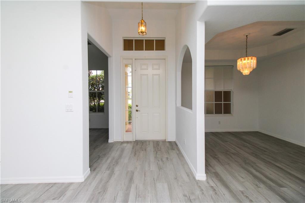 3927 Aurora Court Naples, FL 34116 - Photo 5 of 26 Entryway with a chandelier and wood finished floors