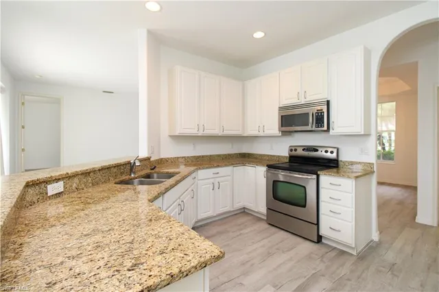 a kitchen with granite countertop a sink stove and microwave