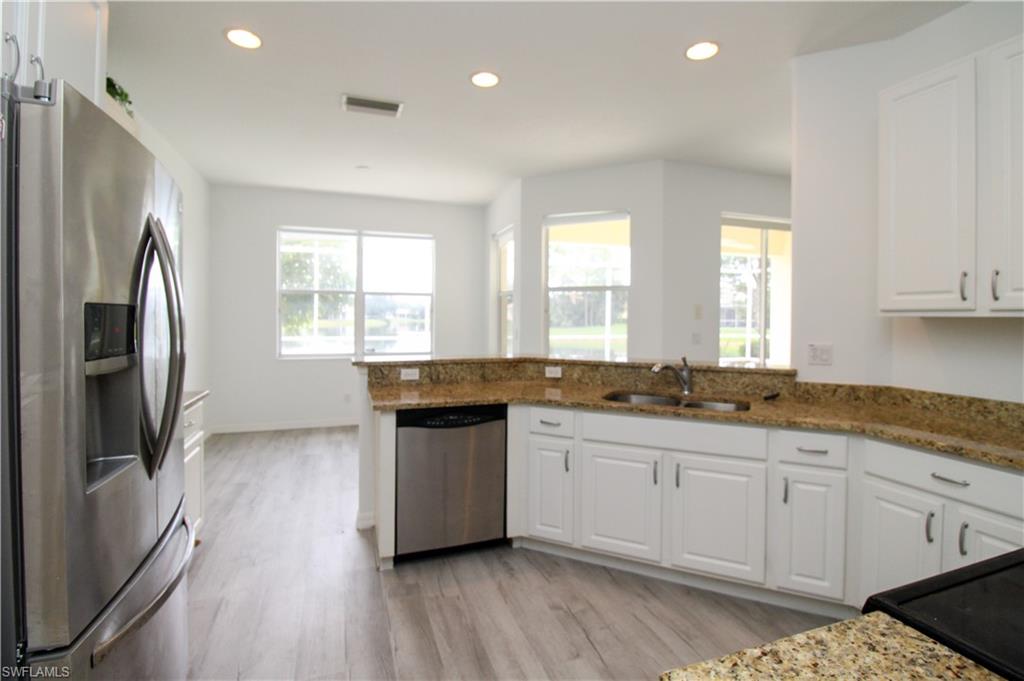 3927 Aurora Court Naples, FL 34116 - Photo 10 of 26 Kitchen featuring appliances with stainless steel finishes, white cabinetry, light stone counters, and recessed lighting