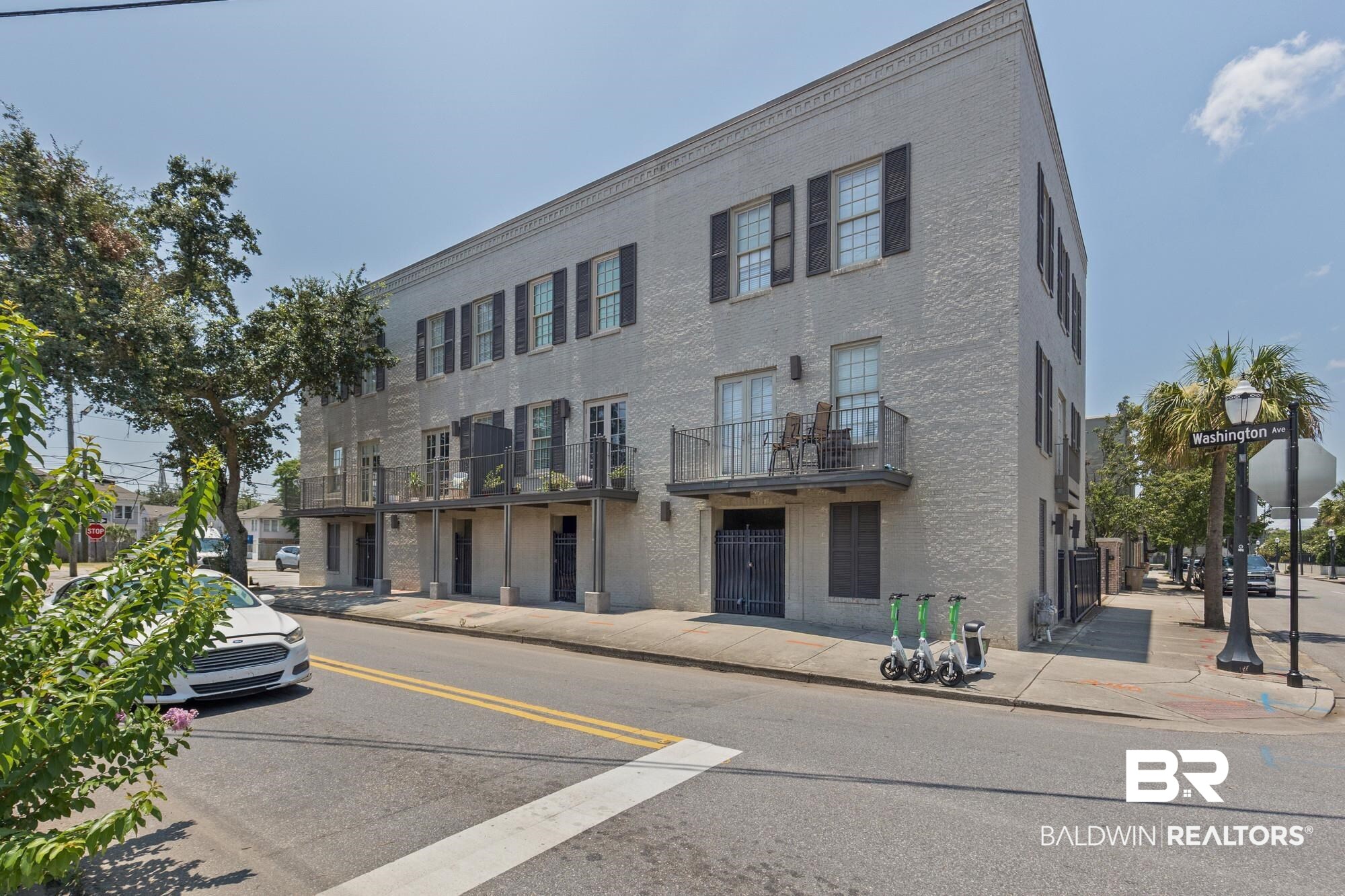 701 Dauphin Street, Unit A Mobile, AL 36602 - Photo 3 of 31 Light-colored brick exterior featuring multiple upper-level balconies with wrought iron railings and double doors