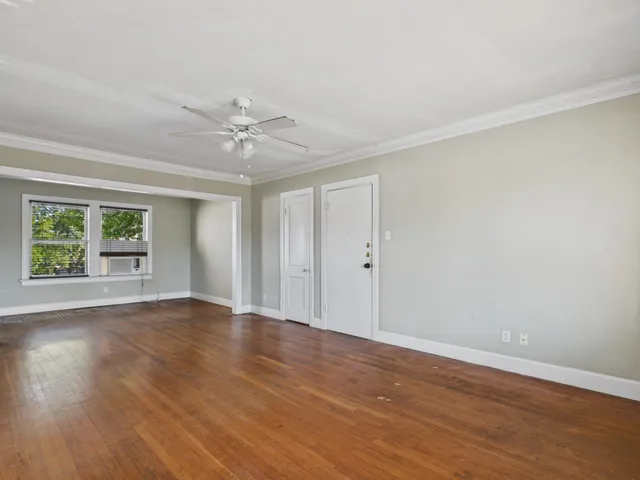 a view of an empty room with wooden floor and a window