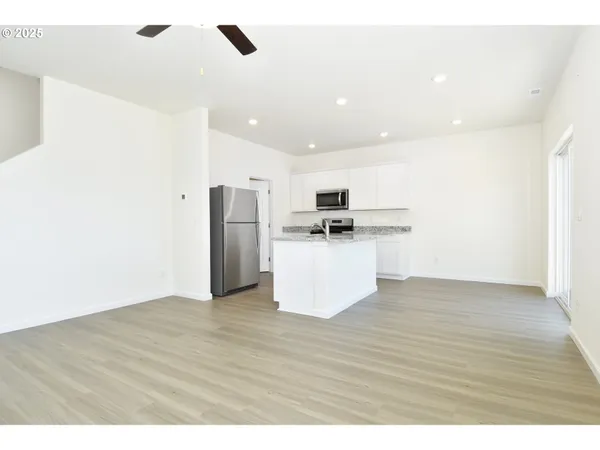 a view of kitchen with stainless steel appliances wooden floor and chair