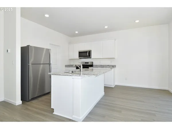 a kitchen with stainless steel appliances granite countertop a refrigerator a sink a stove a microwave and a refrigerator