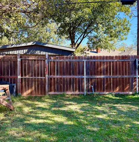 a view of a yard with large trees and wooden fence