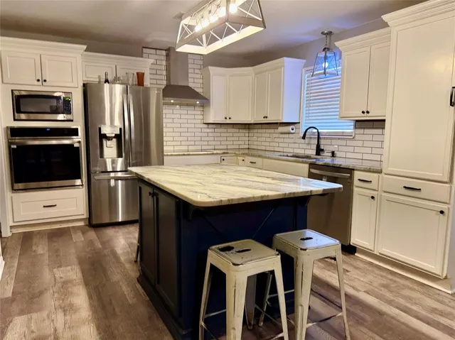 a kitchen with stainless steel appliances a sink a stove a refrigerator and cabinets