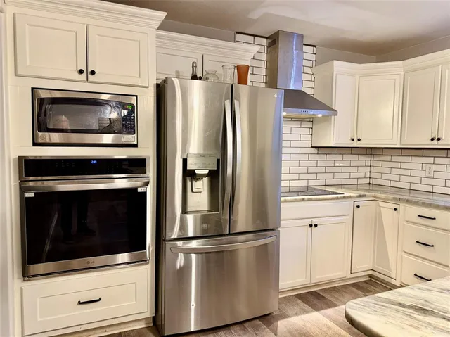 a kitchen with granite countertop white cabinets and stainless steel appliances
