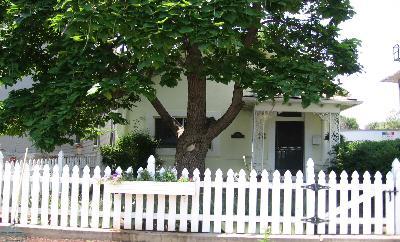 a view of a white house with a small yard and wooden fence