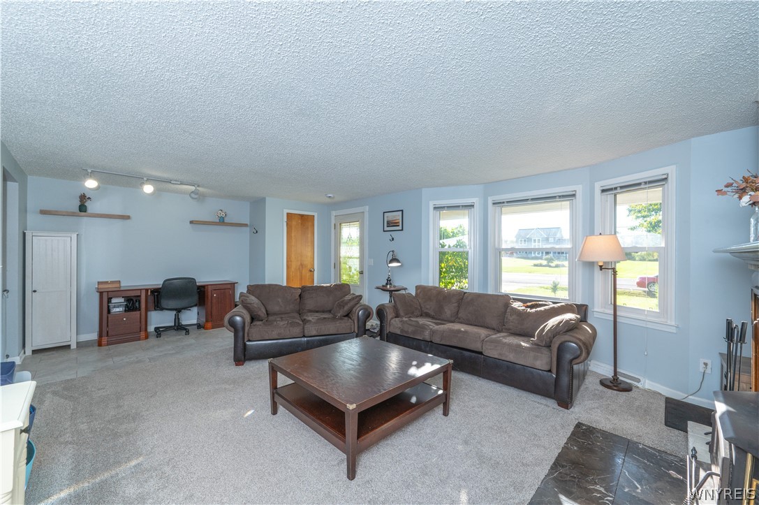 6463 Ward Road Sanborn, NY 14132 - Photo 9 of 49 Bay windows fill this versatile living area featuring textured ceilings and neutral carpeting.