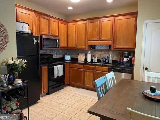 a kitchen with stainless steel appliances a refrigerator a sink a stove cabinets and a dining table