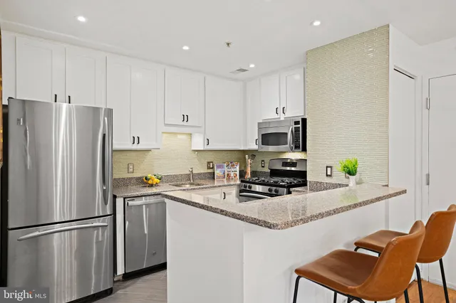 a kitchen with stainless steel appliances granite countertop a refrigerator stove microwave and white cabinets