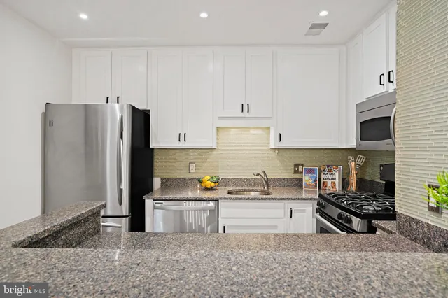 a kitchen with stainless steel appliances granite countertop a refrigerator stove top oven and sink