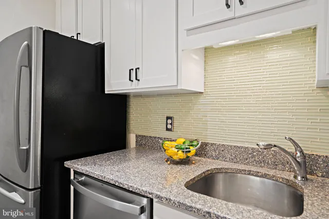 a kitchen with stainless steel appliances granite countertop a sink and a refrigerator