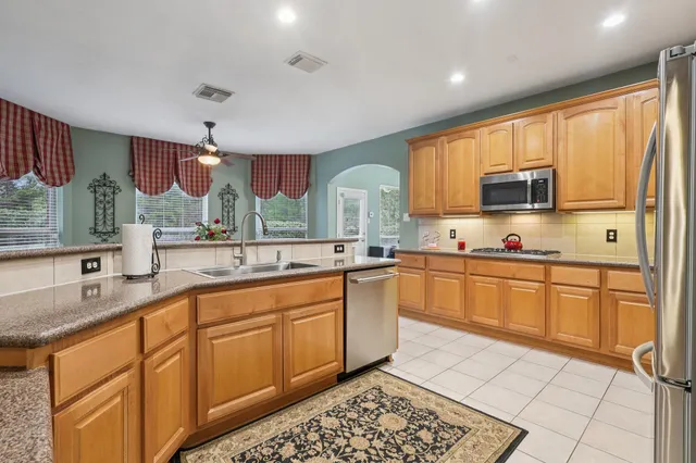 a large kitchen with stainless steel appliances granite countertop a sink and cabinets