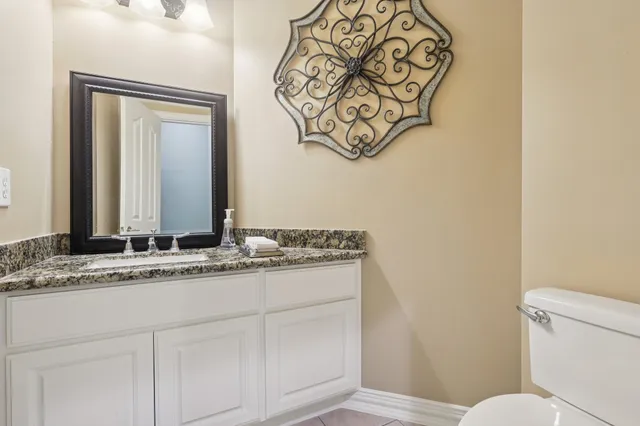 a bathroom with a granite countertop sink mirror vanity and toilet