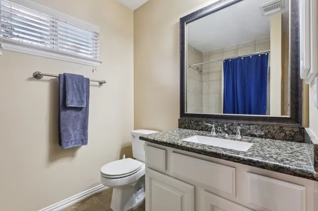 a bathroom with a granite countertop toilet sink and mirror
