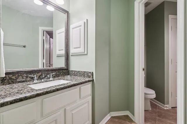 a bathroom with a granite countertop sink a toilet and a mirror