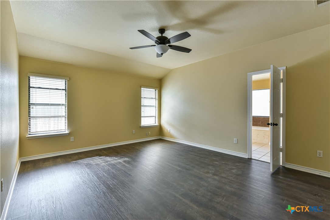 6905 Deorsam Loop Killeen, TX 76542 - Photo 12 of 21 an empty room with wooden floor a ceiling fan and windows