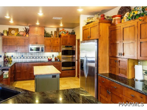 7501 Dillon Wash Road Prescott, AZ 86305 - Photo 5 of 23 a kitchen with stainless steel appliances kitchen island granite countertop a refrigerator a stove and a sink with wooden cabinets